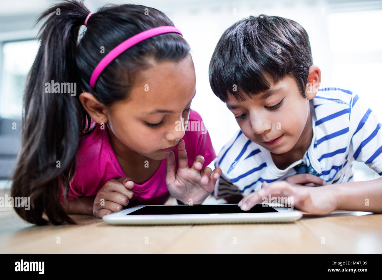 Brother and sister lying on floor and using digital tablet Stock Photo ...
