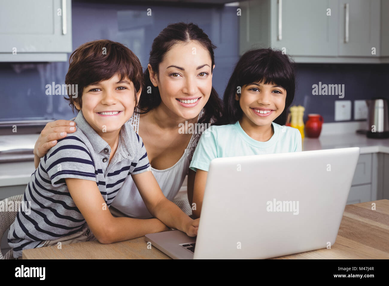 Portrait of smiling mother and children using laptop Stock Photo - Alamy