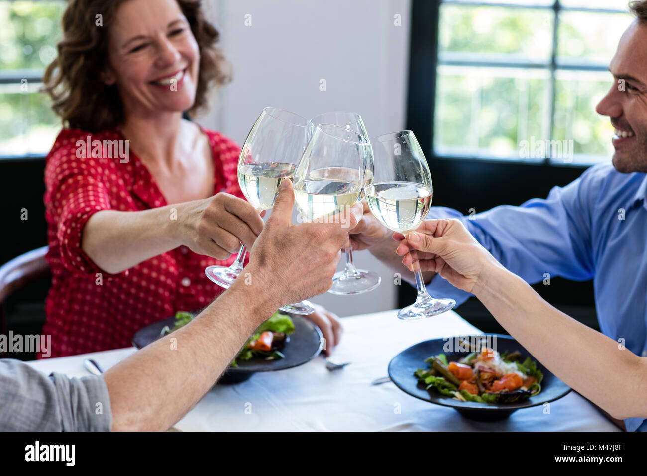 Happy friends toasting wine glass while having lunch Stock Photo