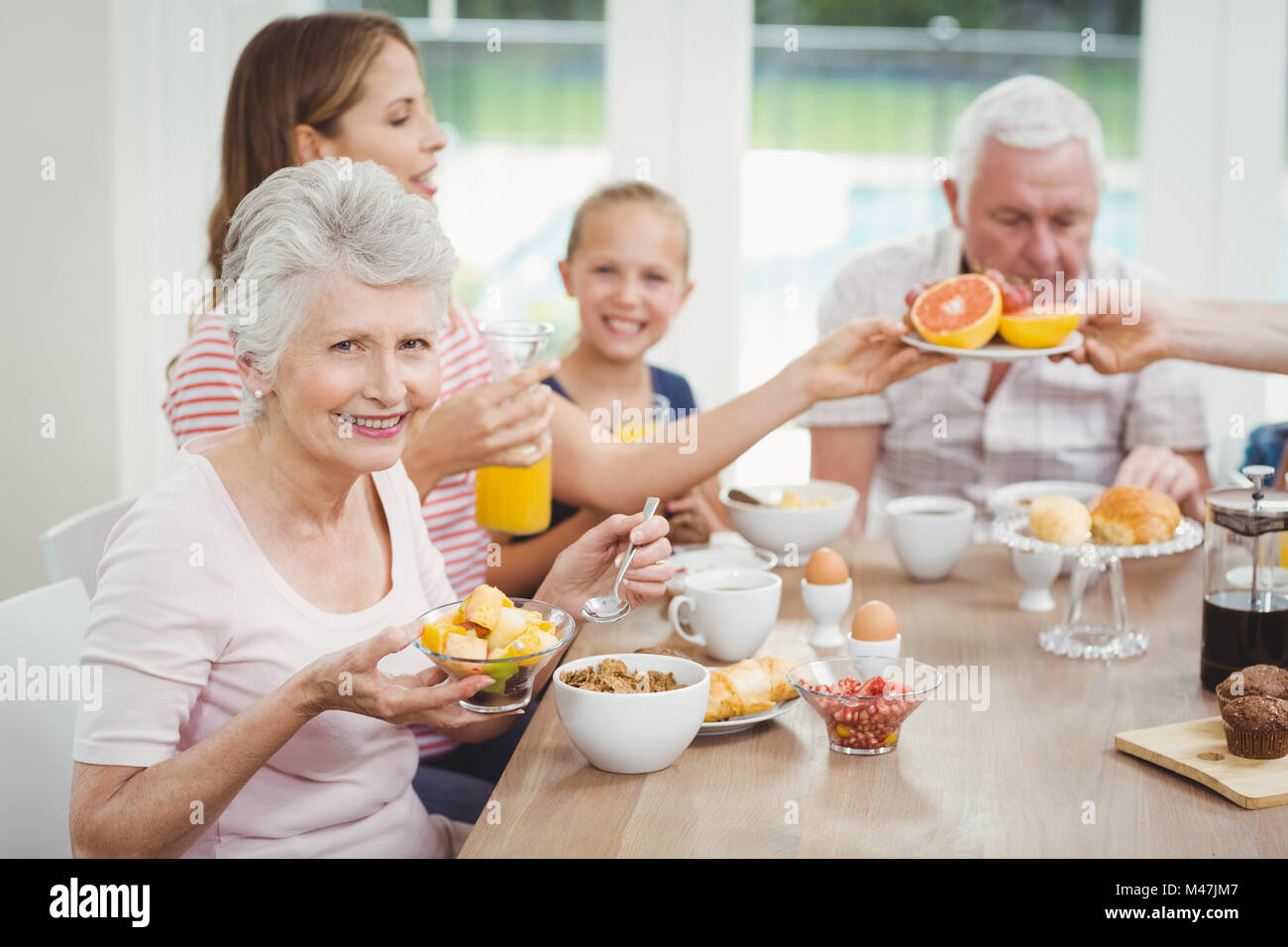 Happy multi-generation family eating fruits during breakfast Stock Photo