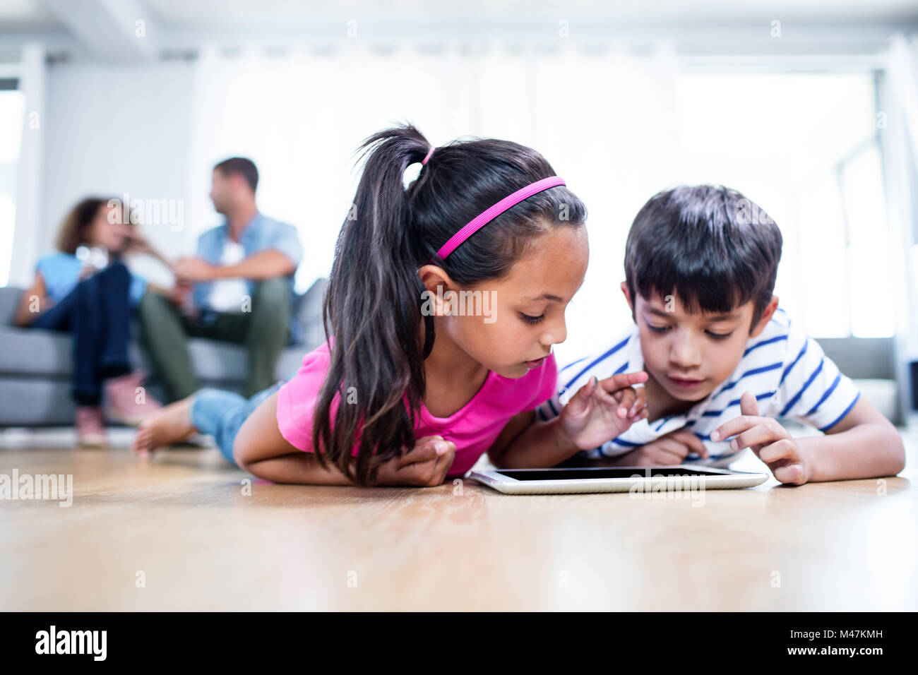 Brother and sister lying on floor and using digital tablet Stock Photo ...