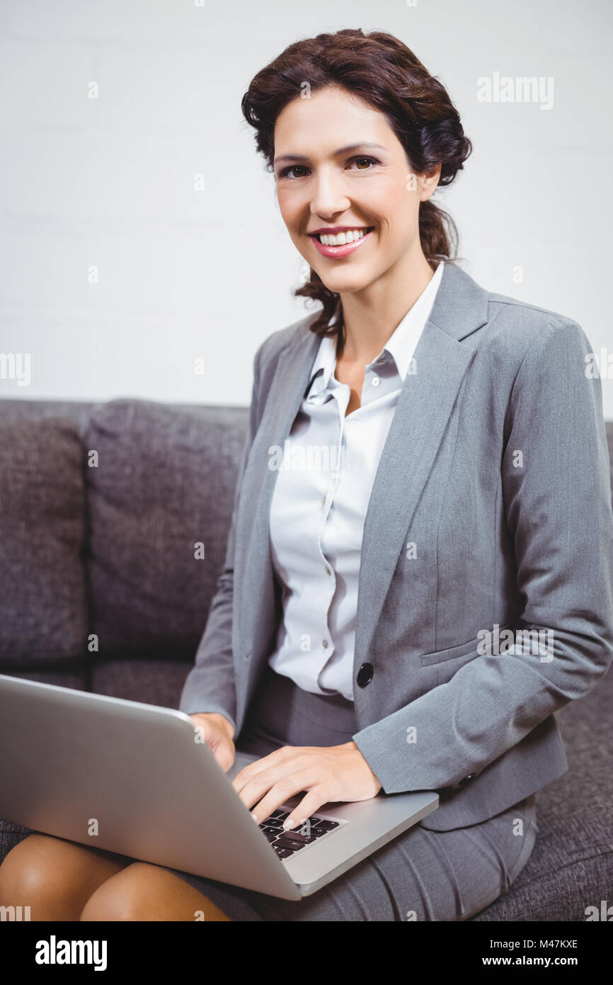 Businesswoman using laptop while sitting on sofa Stock Photo - Alamy