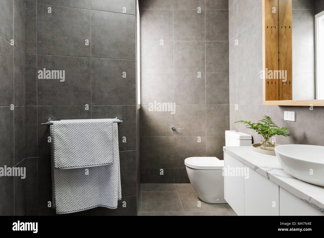 Charcoal grey modern bathroom with marble benctop and wood mirror Stock