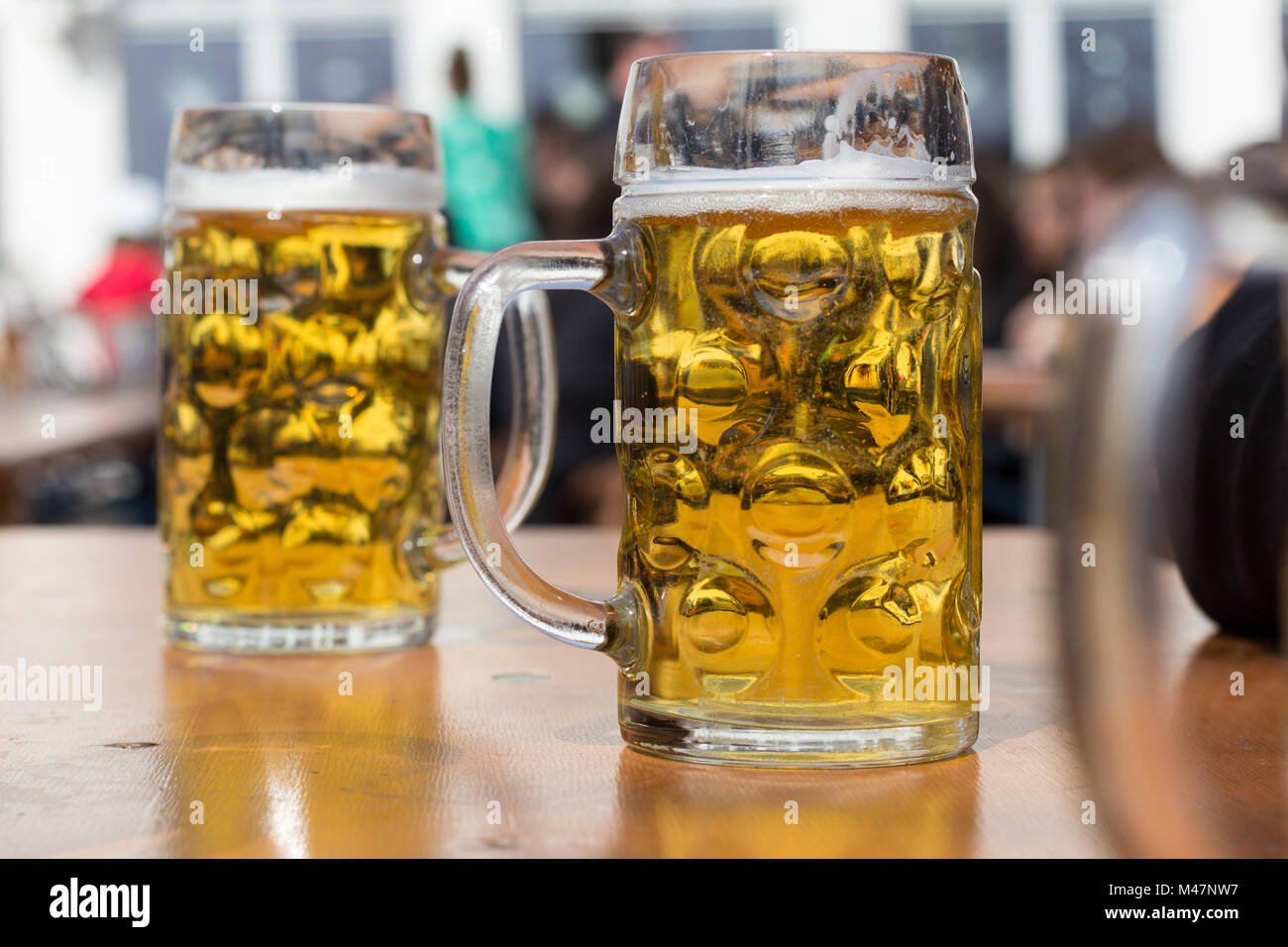 two beer glasses in german biergarten background Stock Photo Alamy