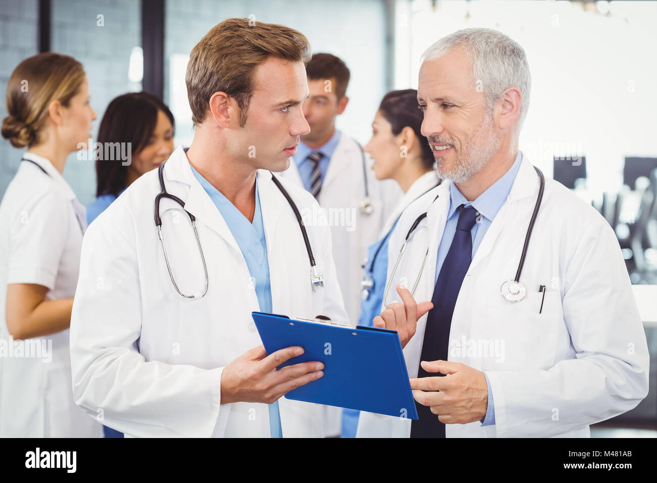 Two doctors looking at clipboard and discussing in hospital Stock Photo ...