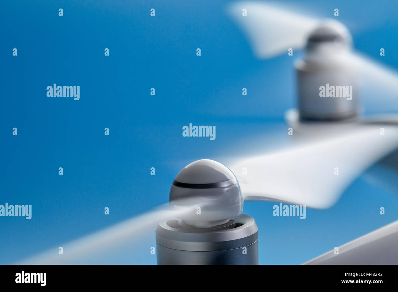 blurred spinning propellers of a drone against blue sky with a copy