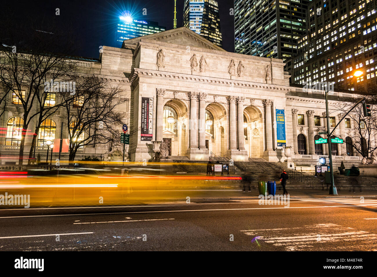 Yellow car passing by the NYPL Stock Photo