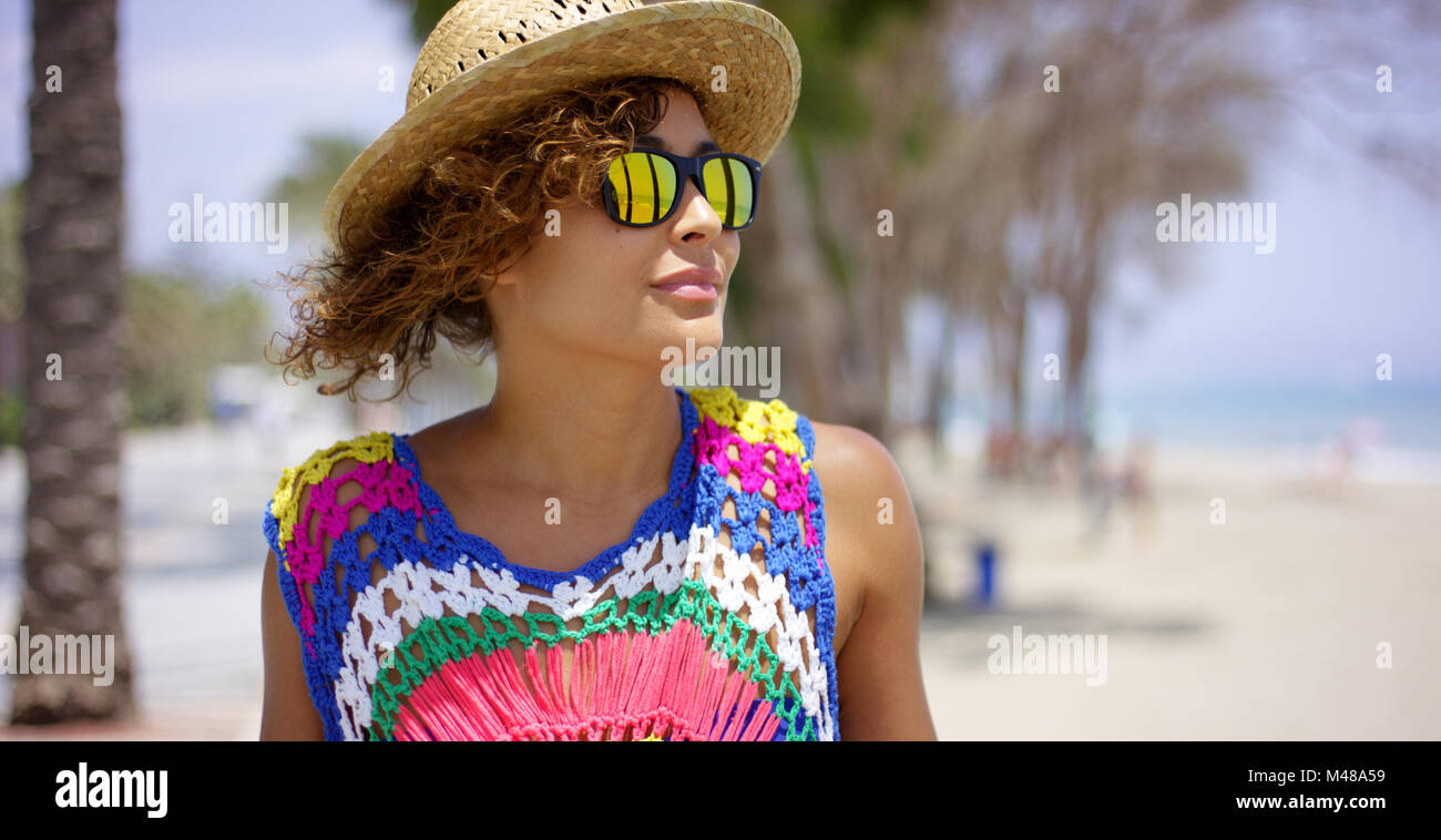 Grinning woman in sunglasses and hat near ocean Stock Photo