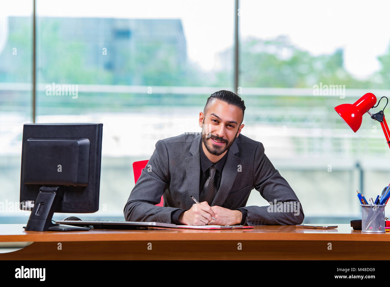 Happy businessman sitting at the desk Stock Photo - Alamy