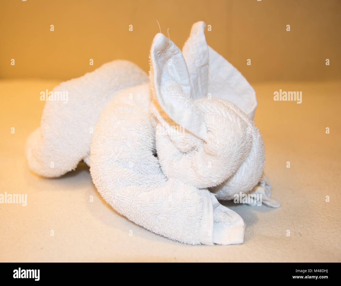 Folded white towel shaped into a bunny rabbit isolated with a neutral