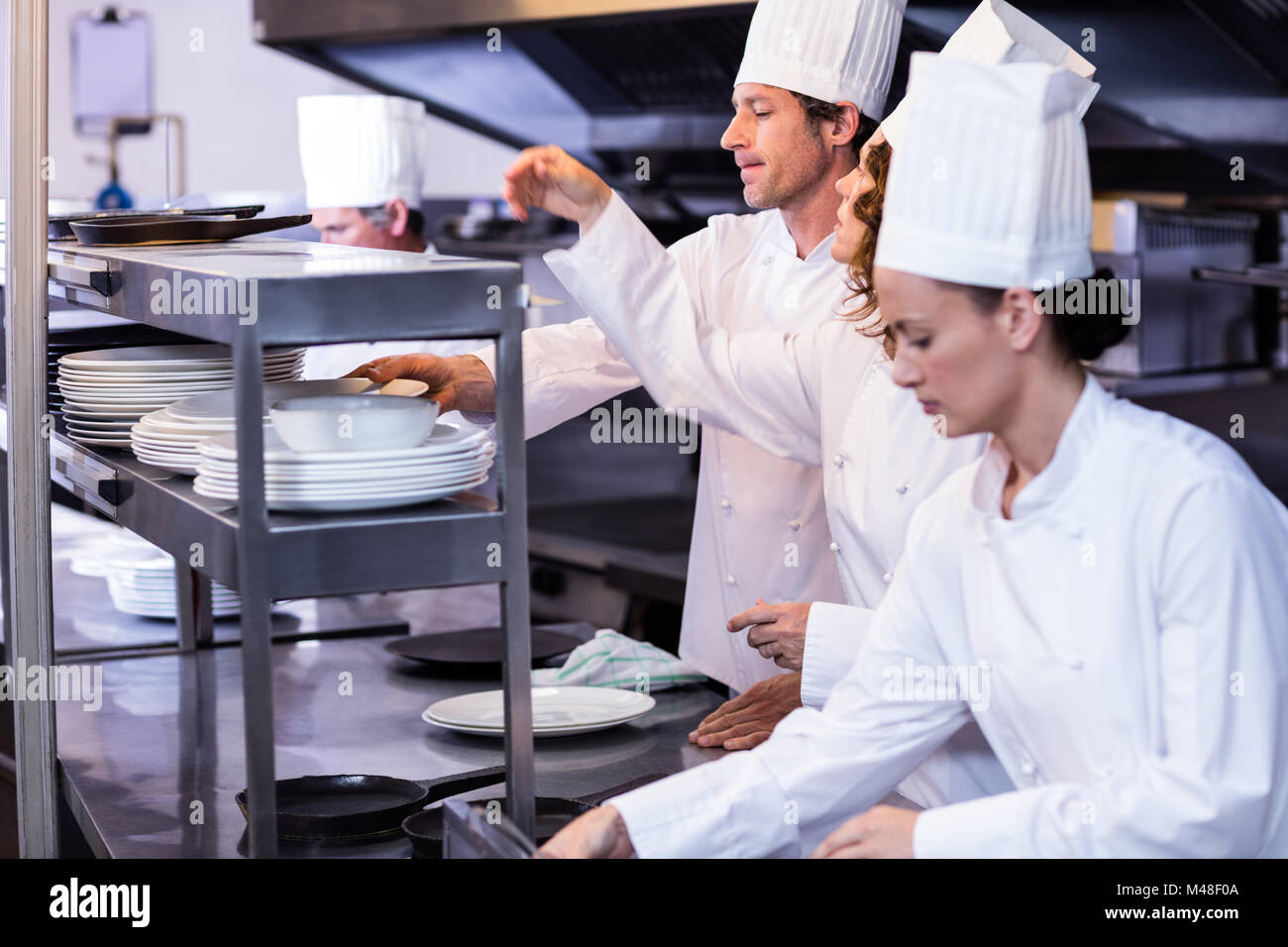 Team of chefs arranging plates on the order station Stock Photo - Alamy