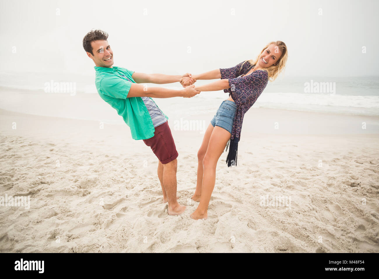 Portrait of happy couple holding hands on the beach Stock Photo - Alamy