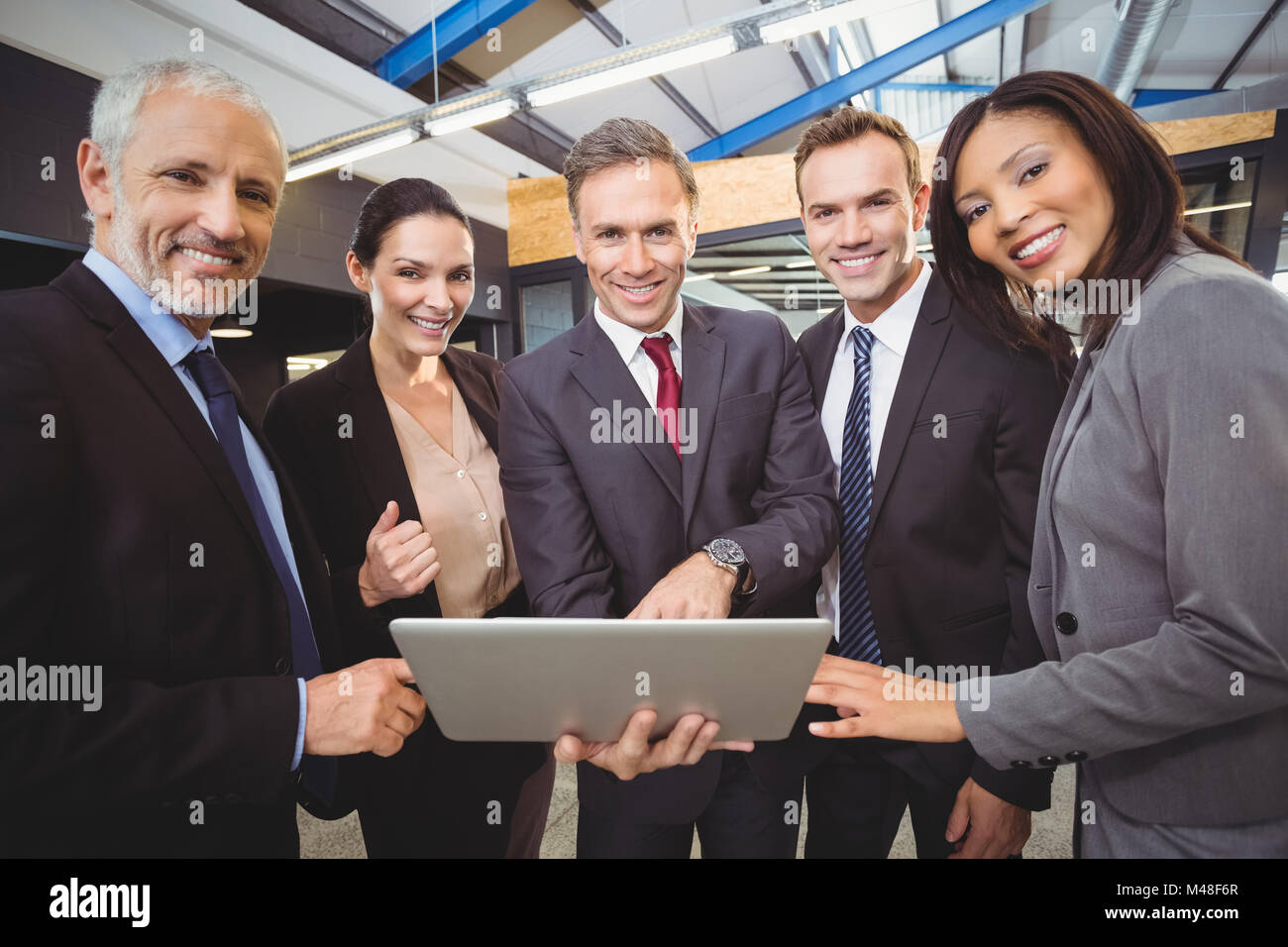 Businesspeople standing together with a laptop Stock Photo - Alamy