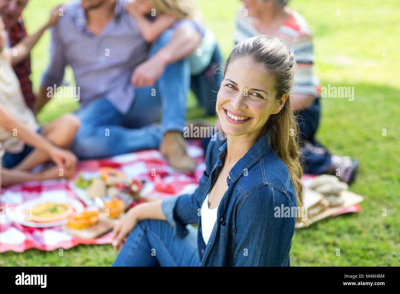 Young woman sitting with family in background at back yard Stock Photo