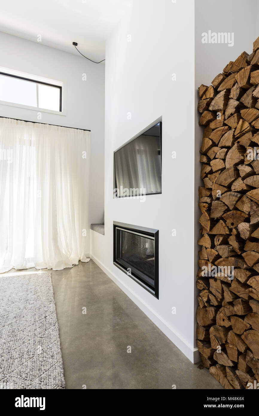Stacked firewood alcove next to living room tv and fireplace Stock Photo