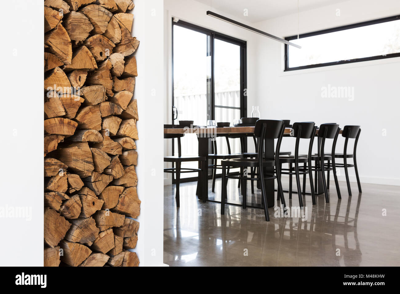 Wood stack feature in lounge with dining table in background Stock Photo