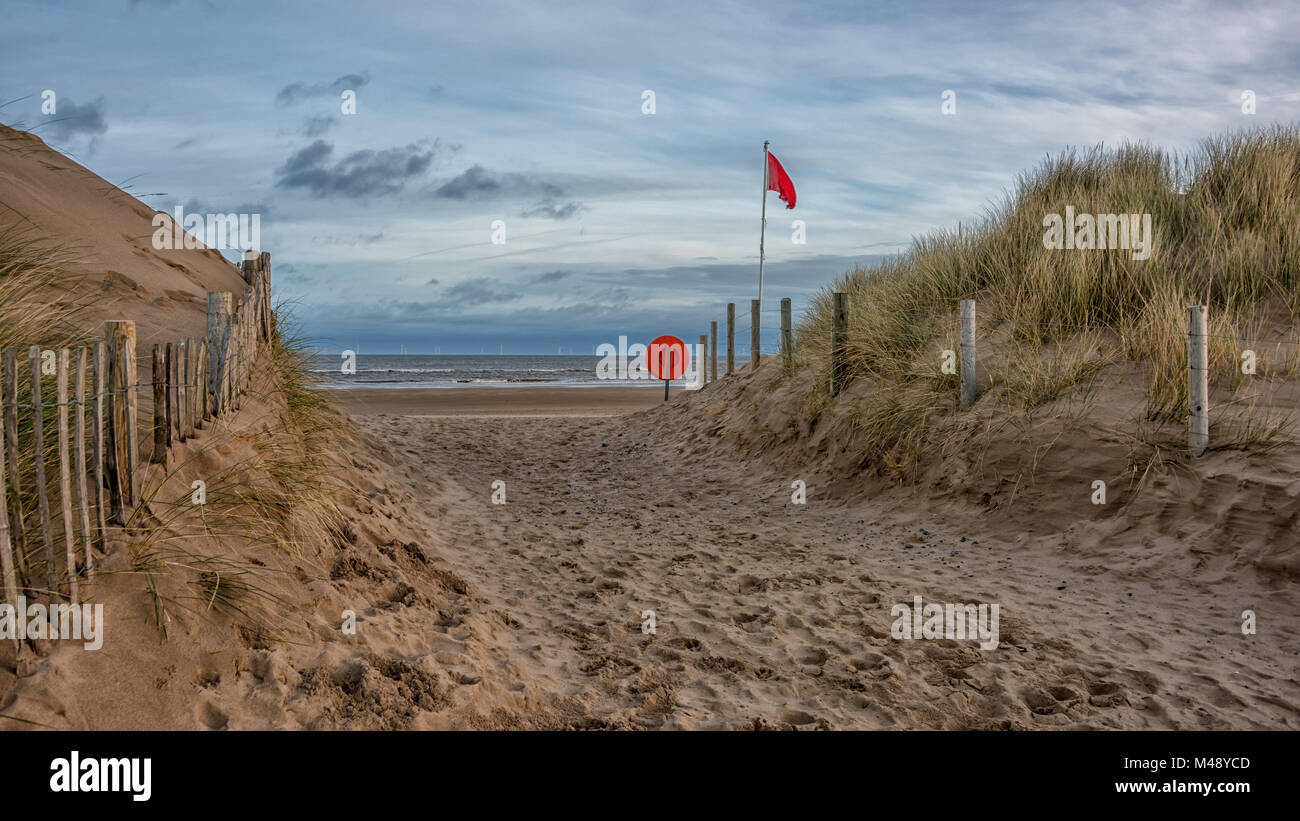 A view of the deserted beach with a path through the sand dunes showing ...