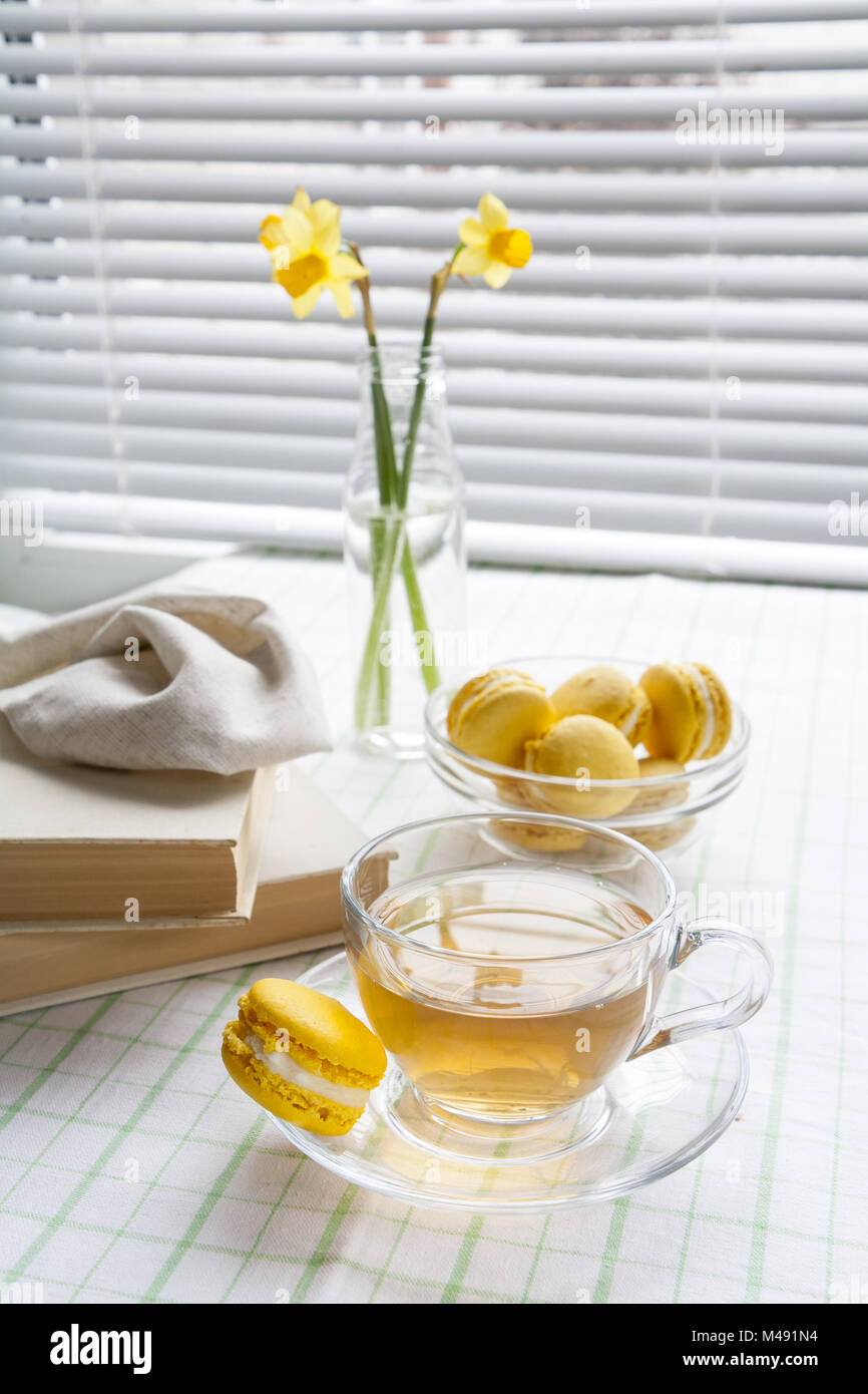 Cup of hot tea, yellow tulips and lemon macaroons Stock Photo