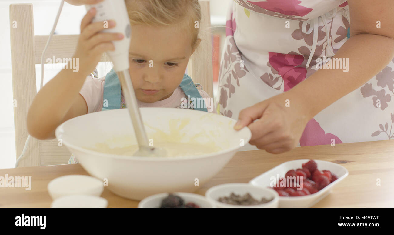 Serious pretty little girl concentrating on baking Stock Photo