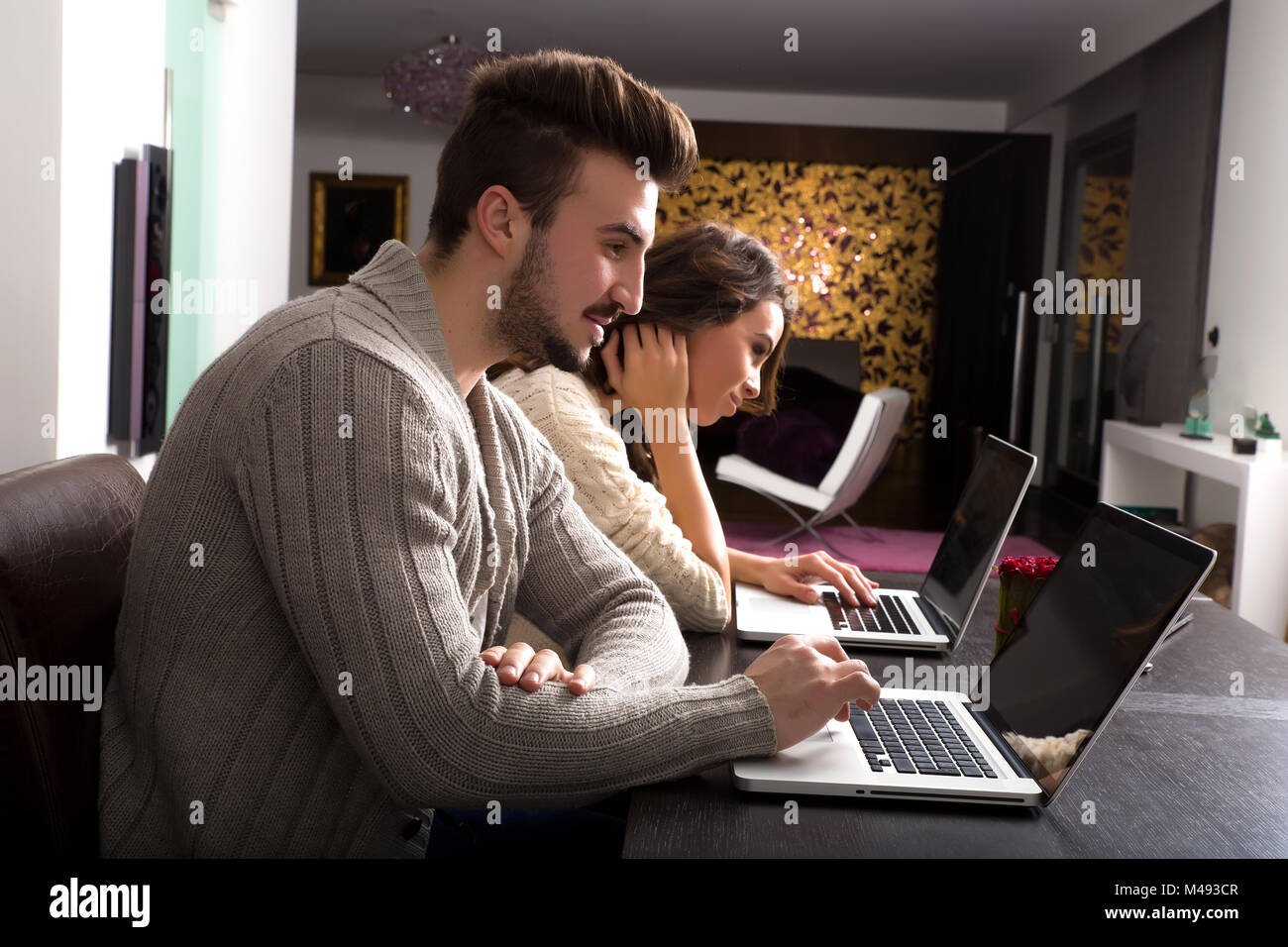 Young couple in front of their Laptop Computers at home Stock Photo - Alamy
