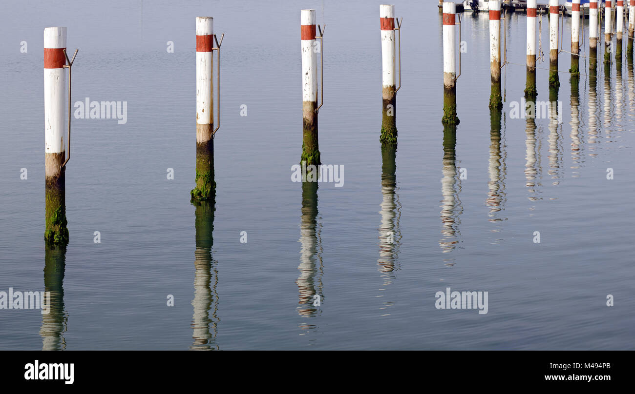 red and white painted poles at a boat jetty Stock Photo