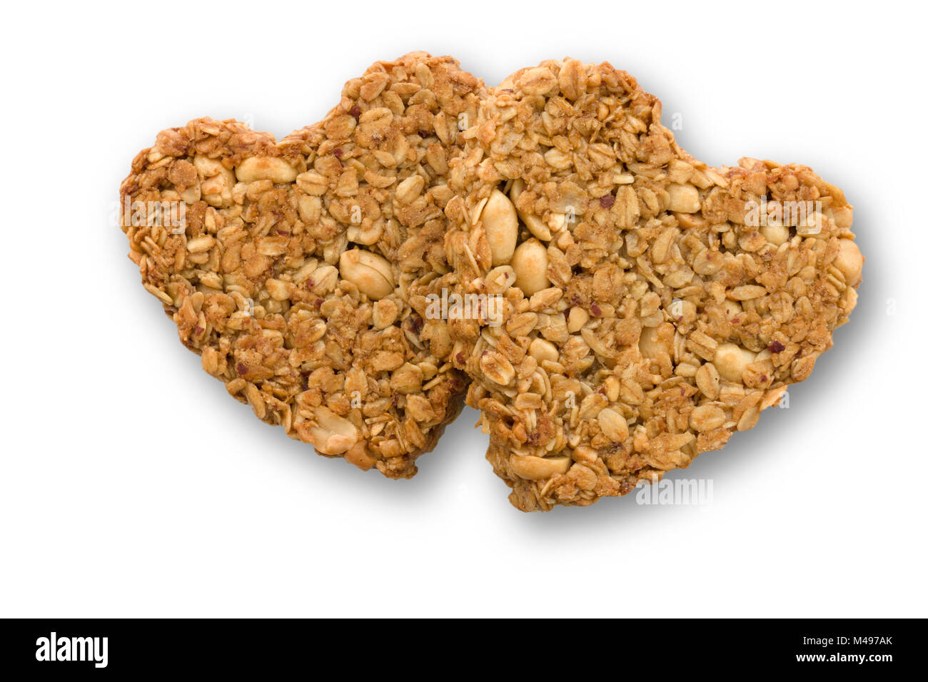Two home-baked heart shaped peanut and oat flapjack biscuits made for Valentines day on white background. Stock Photo