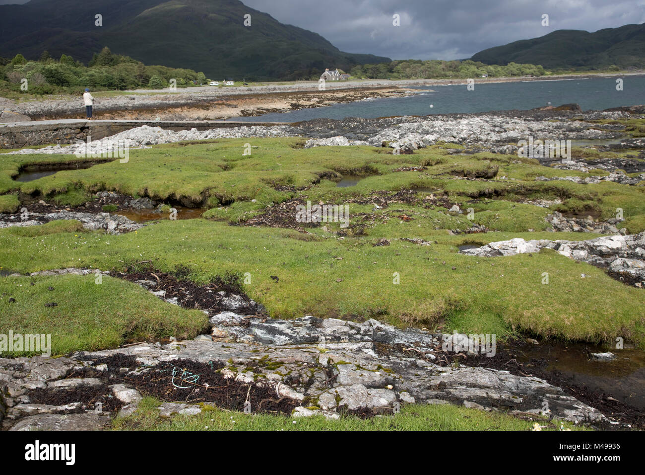 Woman tourist on slipway viewing rocky beach at lowtide Lochbuie Isle