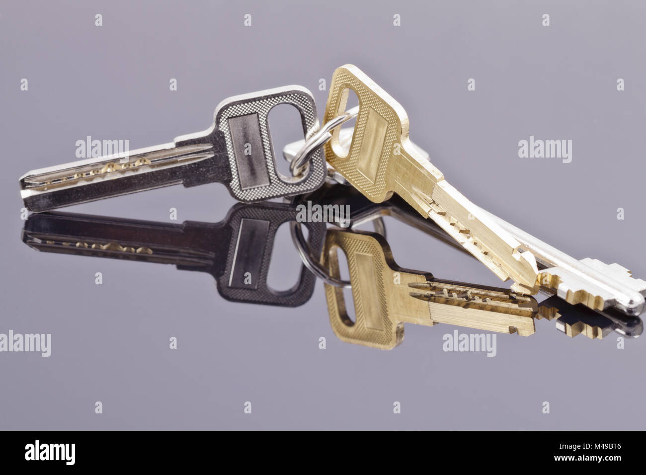 A bunch of keys lying on a black reflective surface Stock Photo