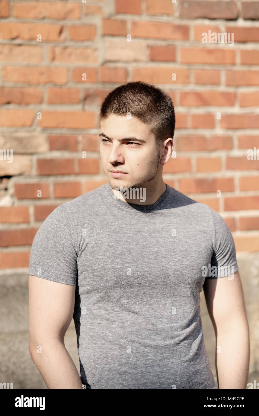 Young man in front of brick wall Stock Photo - Alamy