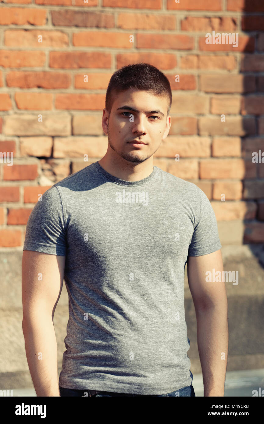 Young man in front of brick wall Stock Photo - Alamy