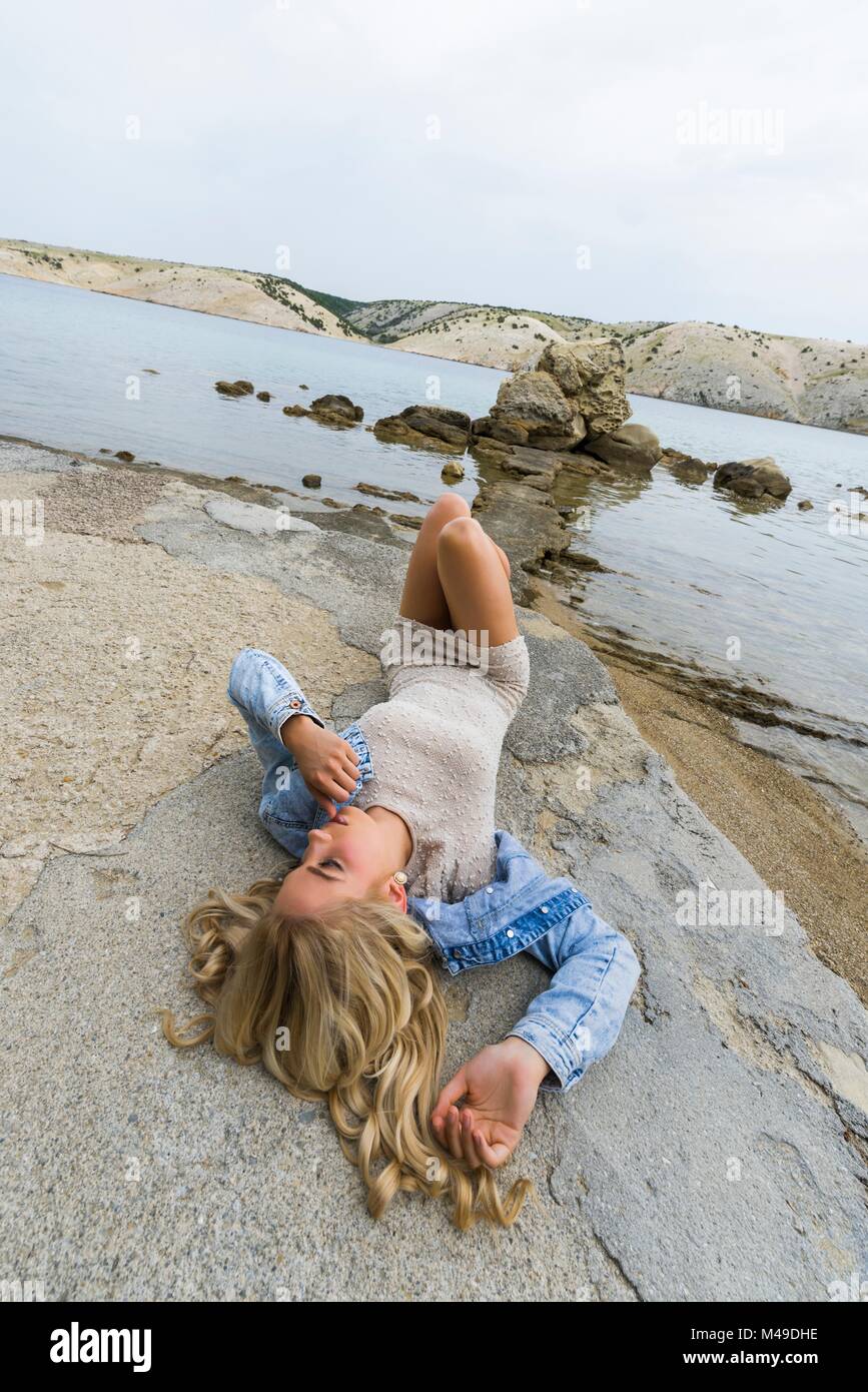 Pretty teen girl lying on back on seaside Stock Photo
