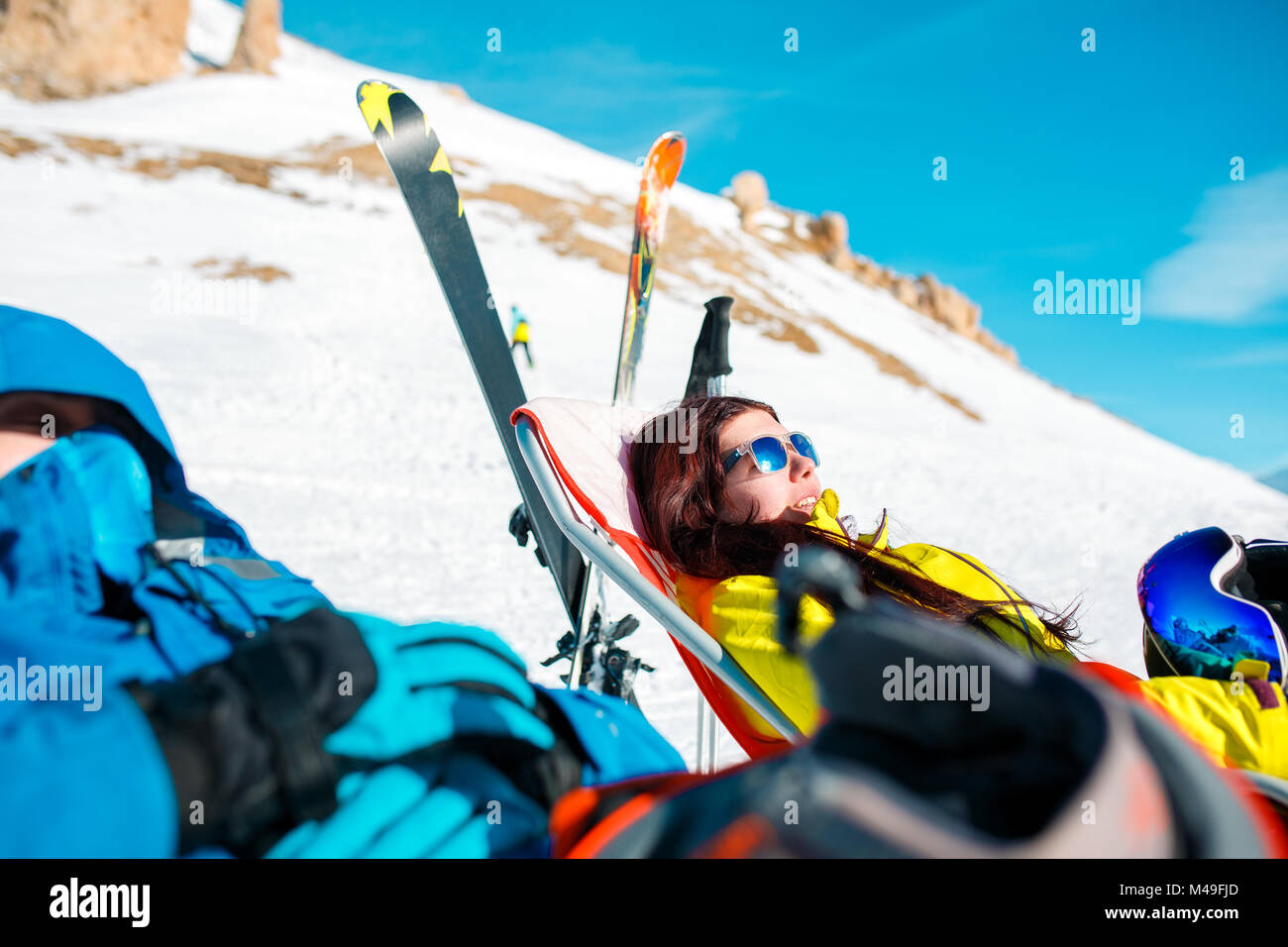 Image of athletes in armchair, skis, sticks in snowy resort Stock Photo