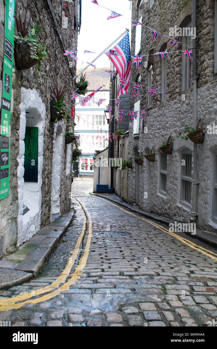 Cobbled street in the Barbican area of Plymouth with British and American flags flying, leading down to the marina, with double yellows lines Stock Photo