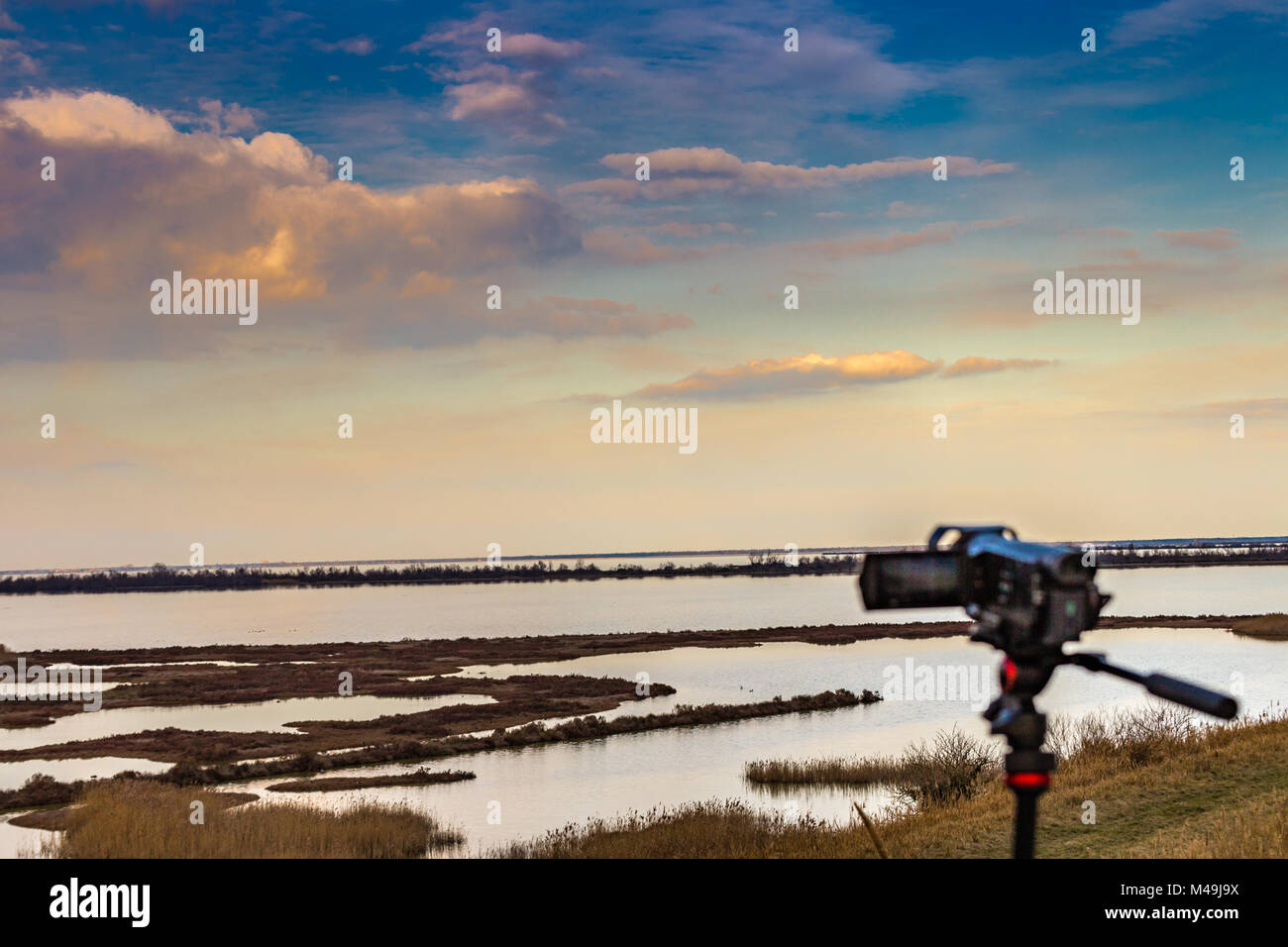 Videography from camcorder on tripod shooting cloudy sky over wild lagoon in winter Stock Photo