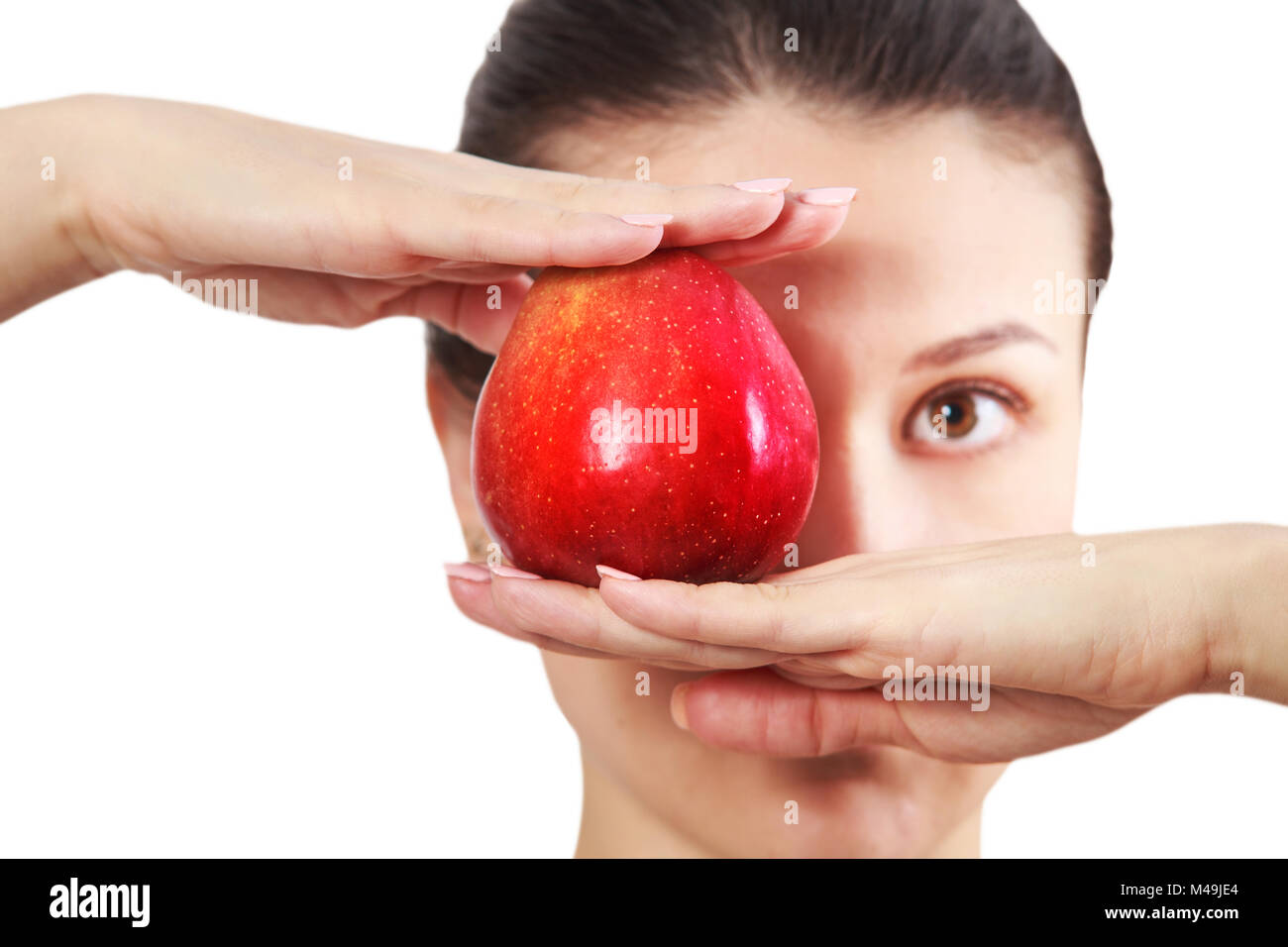 Diet concept. Brunette girl holding red apple at face level isolated on white background. Stock Photo