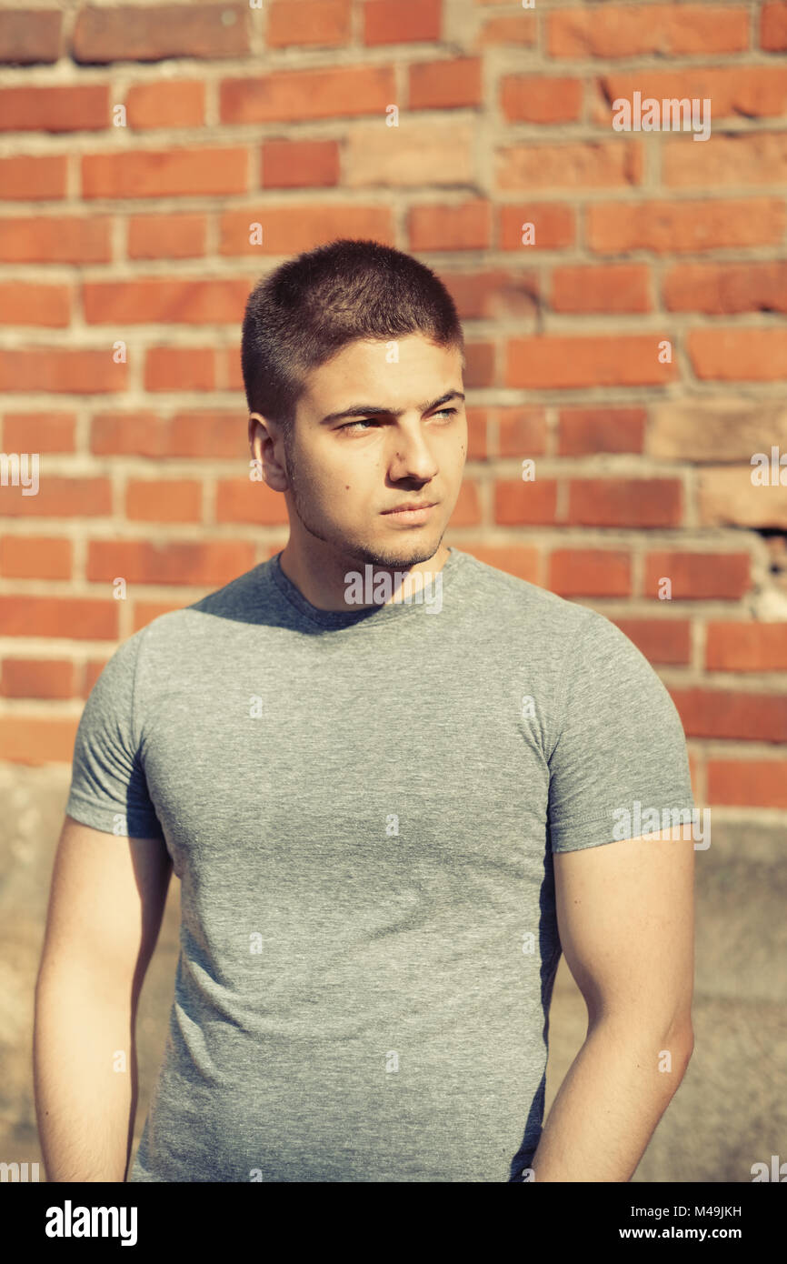 Young man in front of brick wall Stock Photo - Alamy