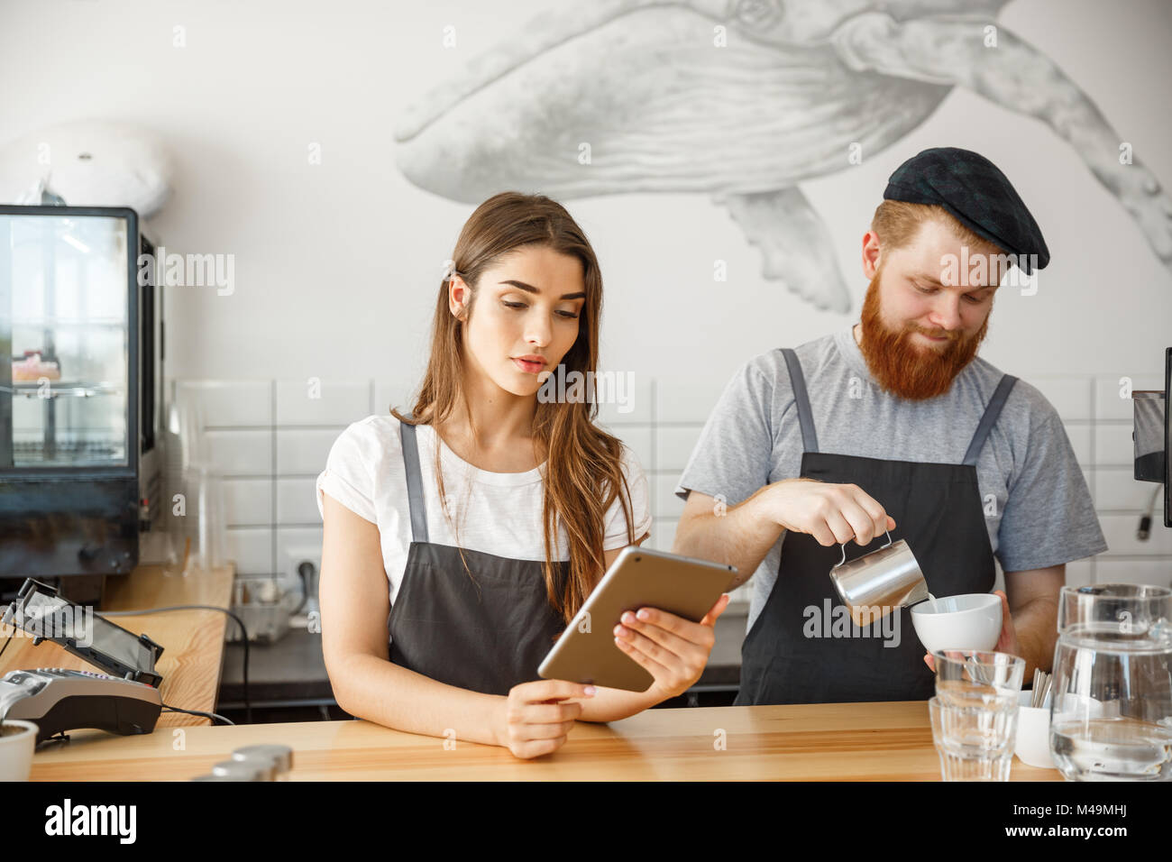 Coffee Business Concept Cheerful baristas looking at their tablets