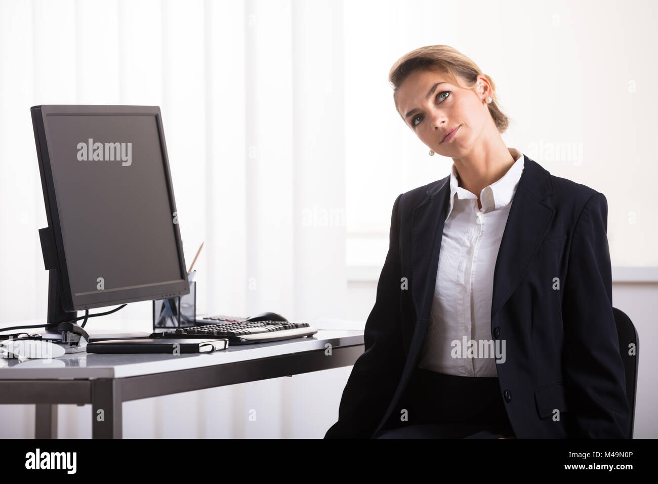 Young Businesswoman Sitting On Chair Exercising Her Neck At Office Stock Photo