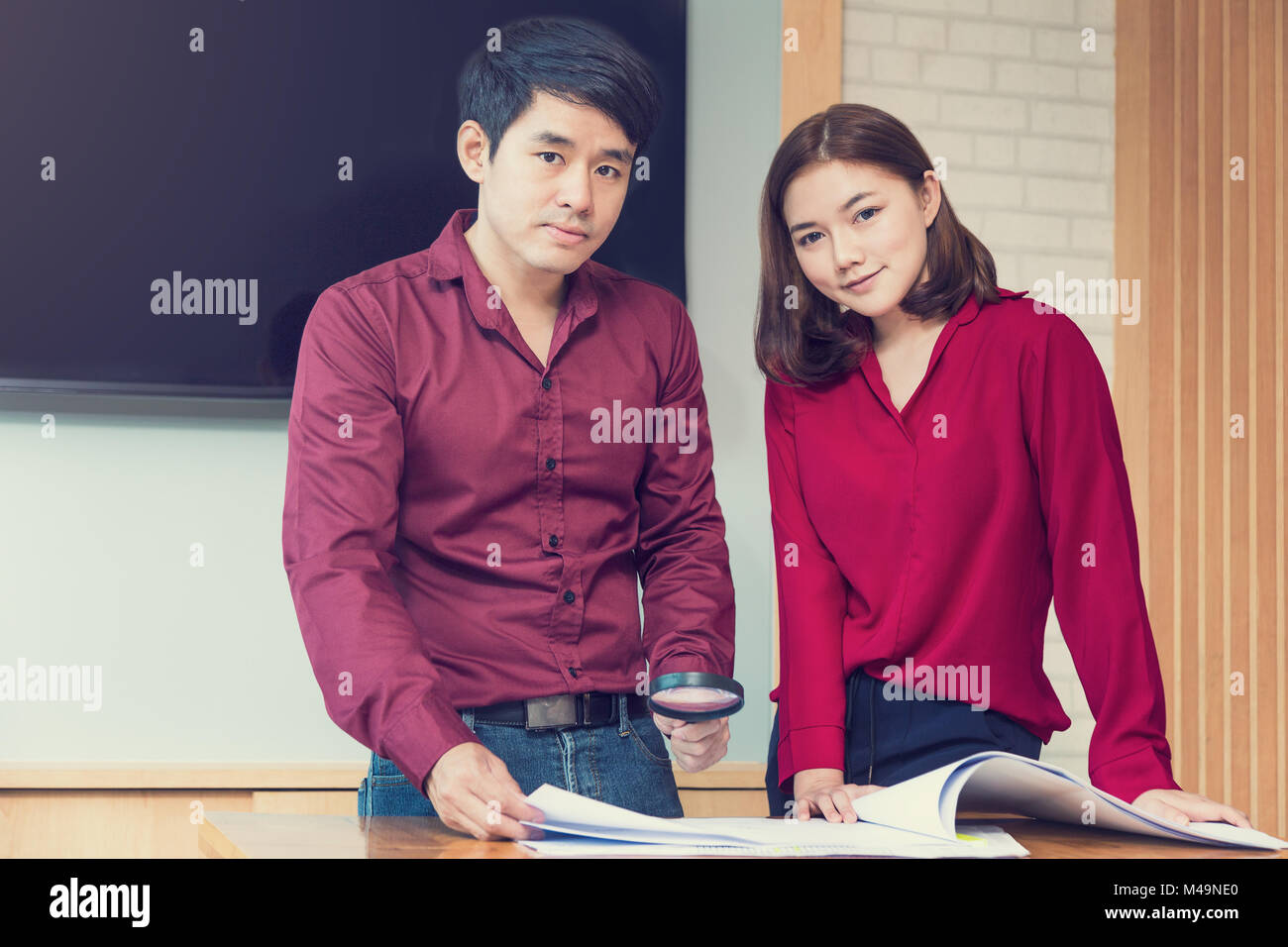 Two happy young successful executives, male and female, working on a project together, smiling at camera, vintage color tone, good for young and succe Stock Photo