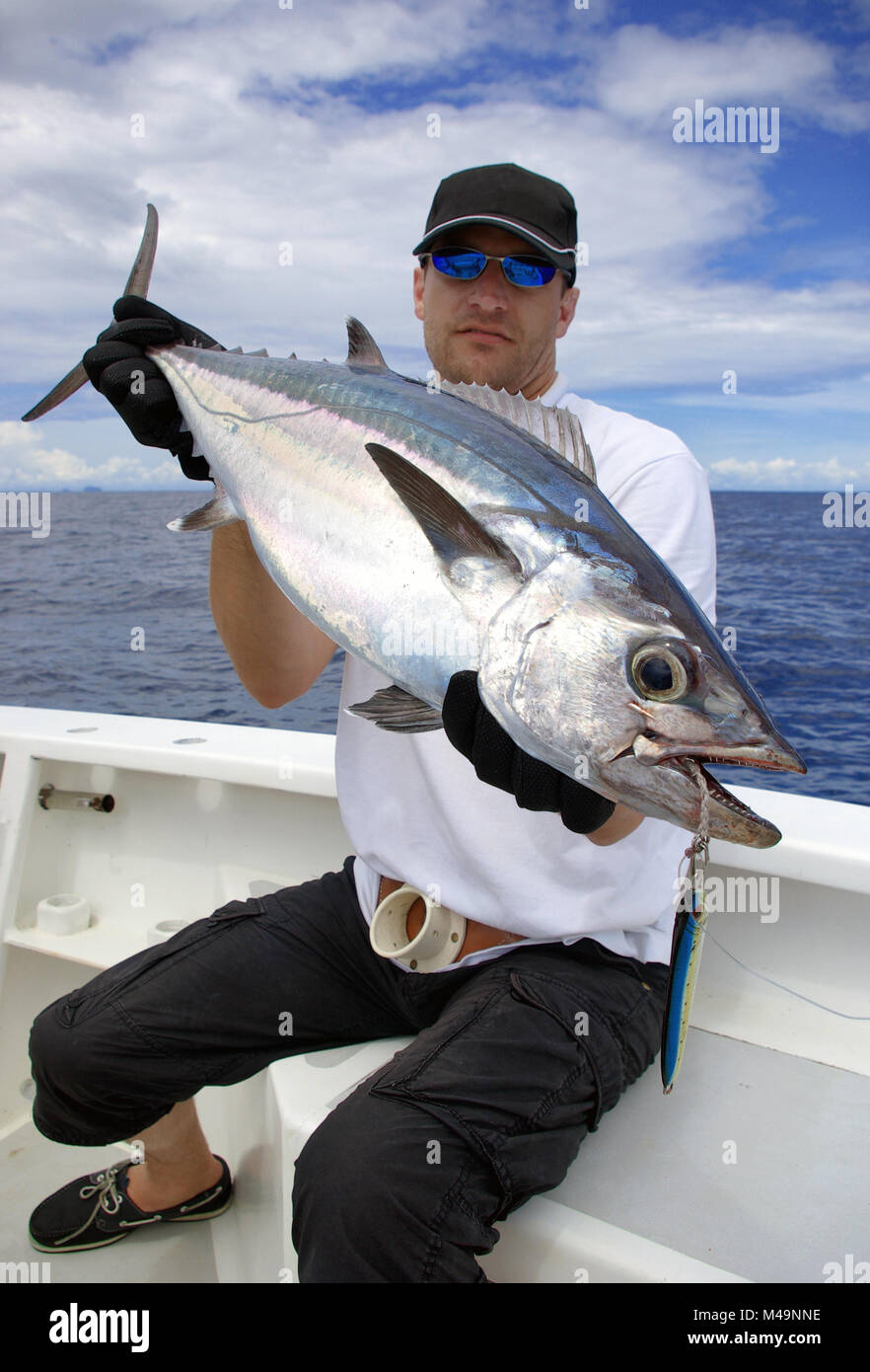 Happy  fisherman holding a tuna fish. Deep sea fishing, big game fishing, catch of fish. Stock Photo