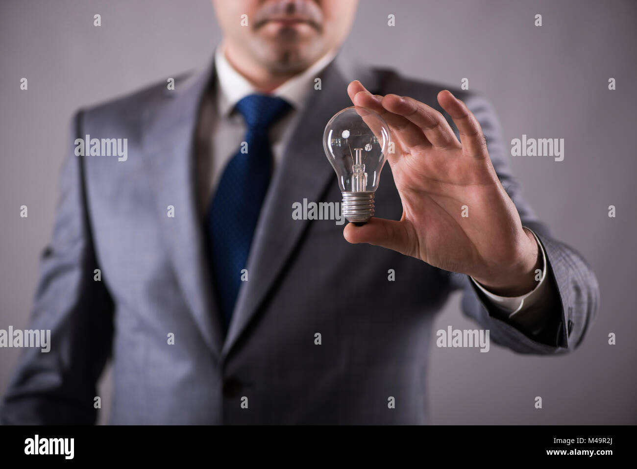 Businessman holding light bulb in creativity concept Stock Photo - Alamy