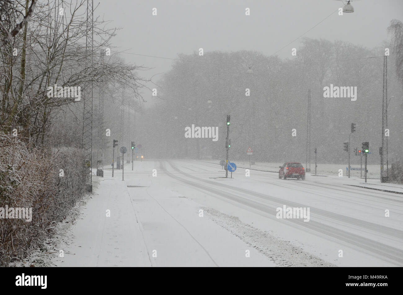 Sparse traffic moving slowly, on a road during heavy snowfall that causes reduced visibility. Stock Photo