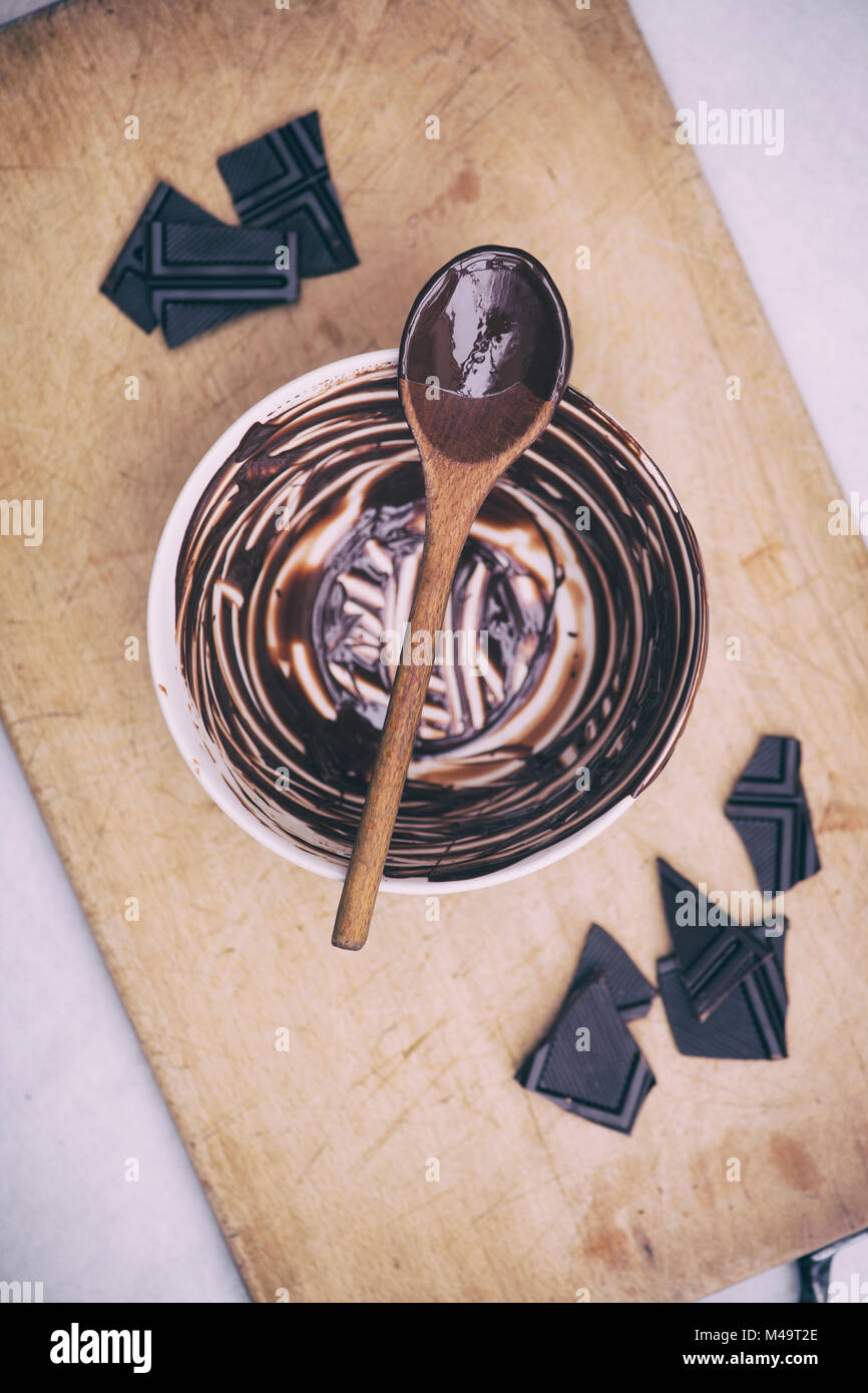 Melted dark chocolate and wooden spoon on a ceramic mixing bowl. Vintage filter applied Stock Photo