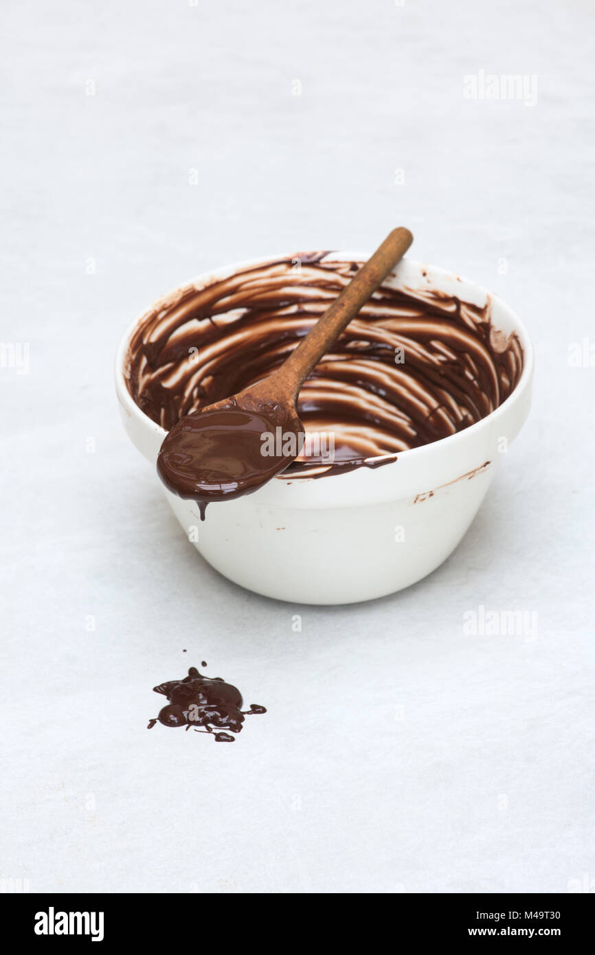 Melted dark chocolate and wooden spoon on a ceramic mixing bowl Stock Photo