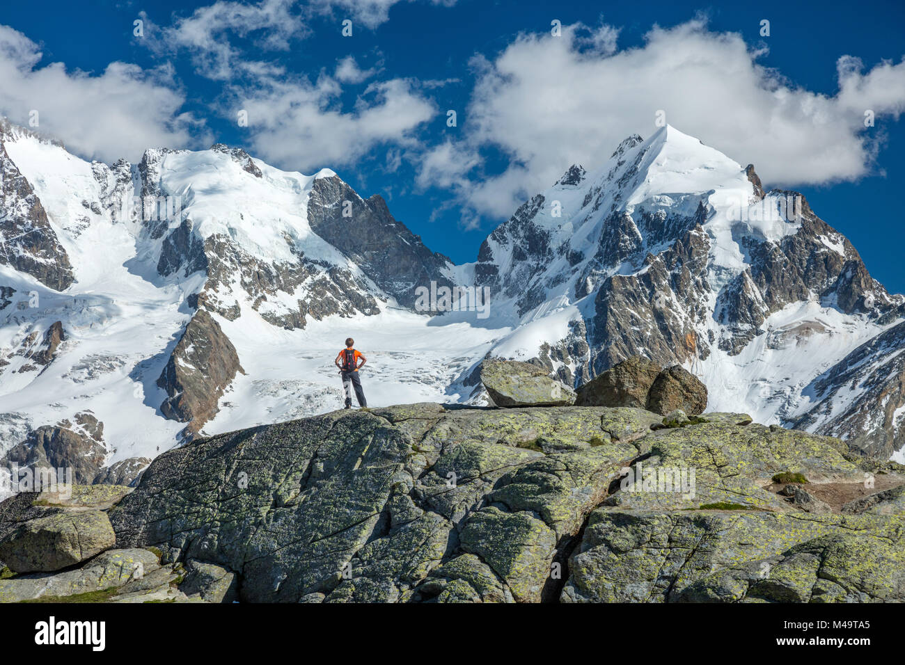 Hiker beneath Piz Bernina and Piz Rosbeg, Fuorcla Surlej, Berniner Alps, Graubunden, Switzerland. Stock Photo