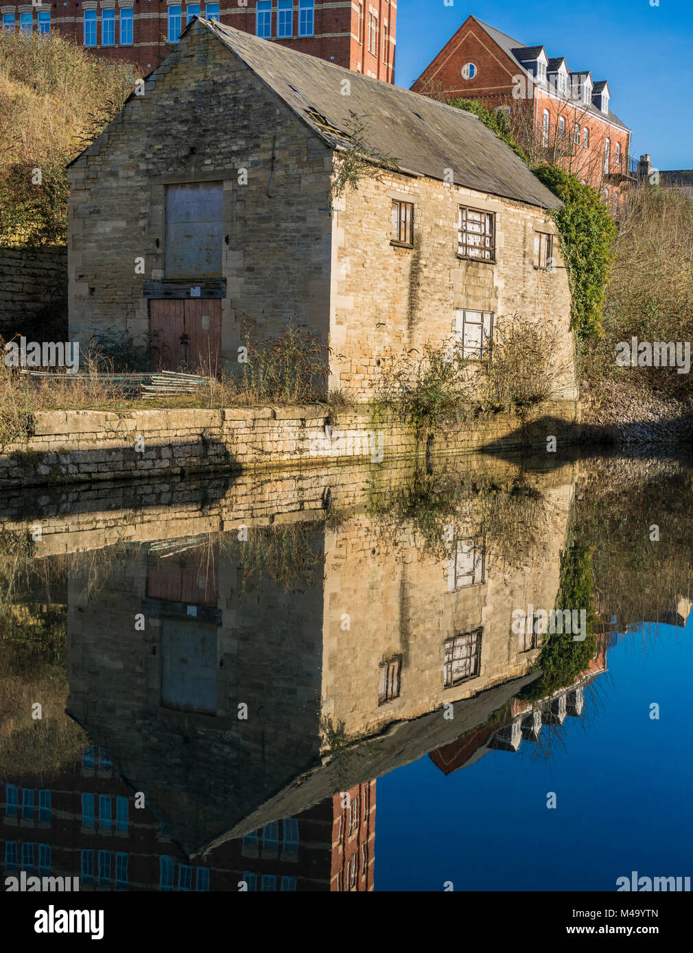 Old building reflecting on water in the restored Stroudwater Canal in Stroud, Gloucestershire, UK Stock Photo