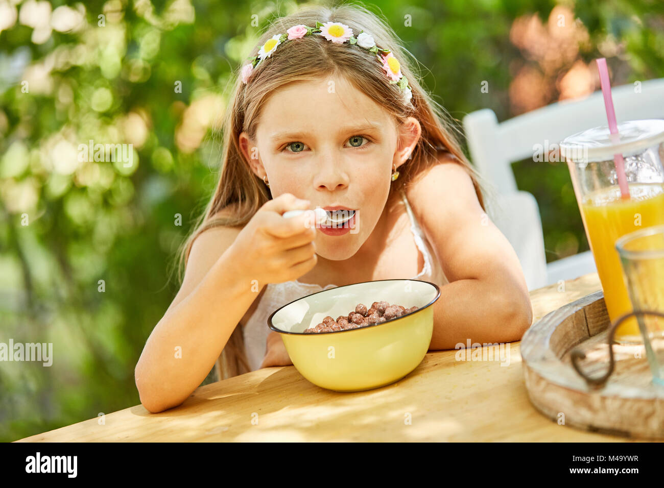 Hungry girl is eating healthy cereal for breakfast in kindergarten Stock Photo