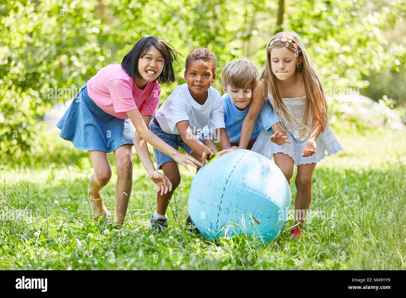 Group of kids plays with world globe in international kindergarten