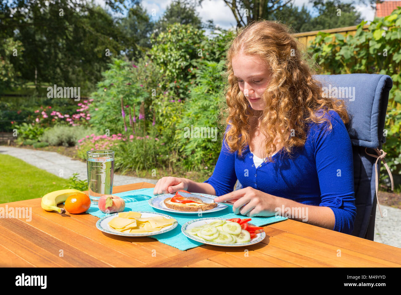 Young caucasian woman eating breakfast in garden Stock Photo