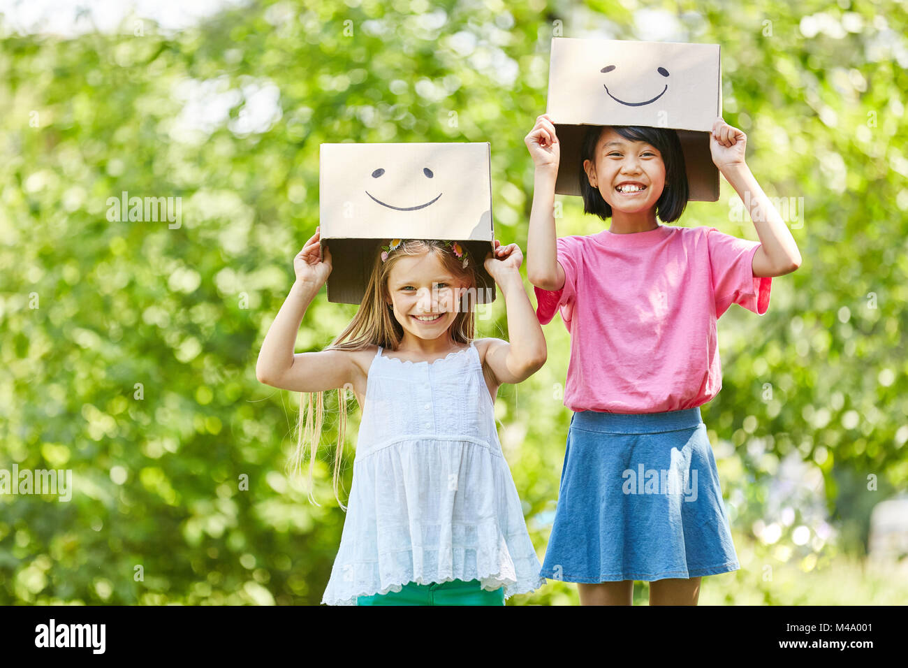 Two girls play with funny painted cardboard boxes in the summer in nature Stock Photo